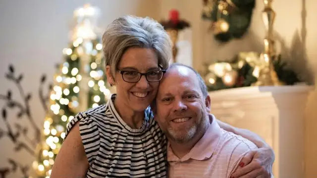 Smiling couple hugging in front of a Christmas tree